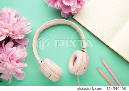 Modern pink headphones with flowers peonies and notebook on mint background Modern pink headphones with flowers peonies and notebook on mint background 114540408