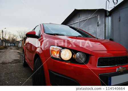 Beautiful red car.Foreground of a red car with headlights on. 114540664