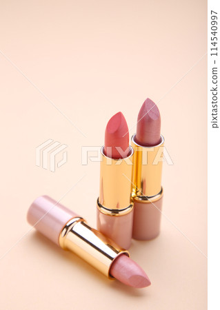 Three lipsticks on beige background, close up 114540997