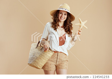 smiling elegant woman in blouse and shorts against beige smiling elegant woman in blouse and shorts against beige 114541233