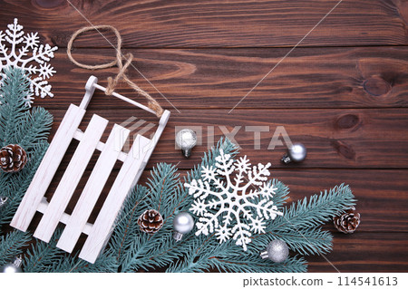 Christmas toy sledge with fir-tree branch on a brown background. Christmas toy sledge with fir-tree branch on a brown background. 114541613