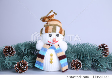 Small snowman toy on a grey background wuth fir-tree branch Small snowman toy on a grey background wuth fir-tree branch 114541648