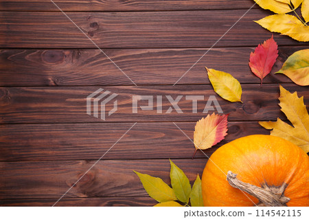 Orange pumpkin with leaves on brown background 114542115