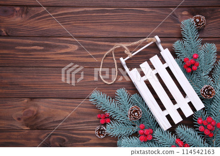 Christmas toy sledge with fir-tree branch on a brown background. Christmas toy sledge with fir-tree branch on a brown background. 114542163