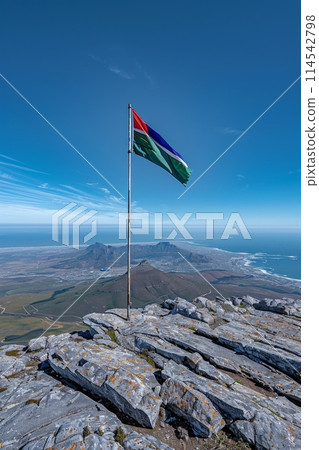 flag of Namibia flutters proudly atop a mountain, symbolizing unity, liberty, and diversity in the stunning natural setting. 114542798