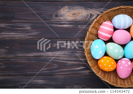 Colorful easter eggs in basket on brown wooden background 114543472