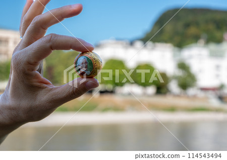 Salzburg, Austria, August 15 2022. A Mozart ball between forefinger and thumb of one hand 114543494