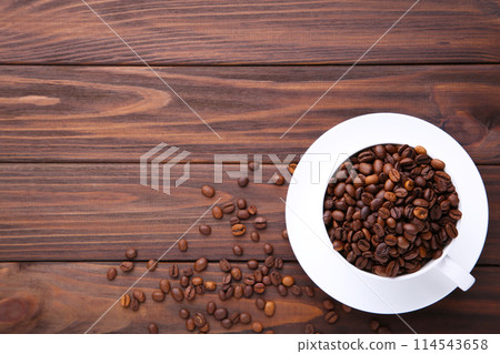 Coffee beans in cup on brown wooden background. Coffee beans in cup on brown wooden background. 114543658