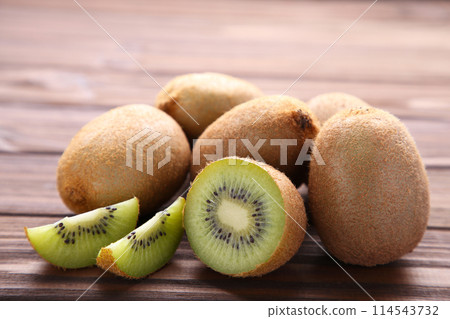 Ripe kiwi fruit and half kiwi fruit on brown background 114543732