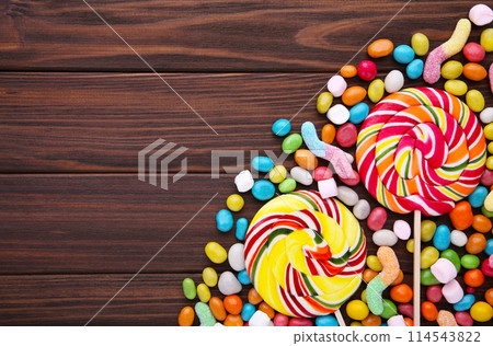 Colorful lollipops and different colored round candy on brown background 114543822