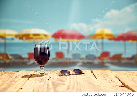 Dark beer standing on wooden table on beach with ocean view. Summer vacation with refreshing drinks 114544340