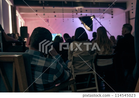 Adults at the conference listen to a lecture by a female speaker who speaks from the stage in a large conference room.The concept of business and entrepreneurship.With space to copy.High quality photo 114545023