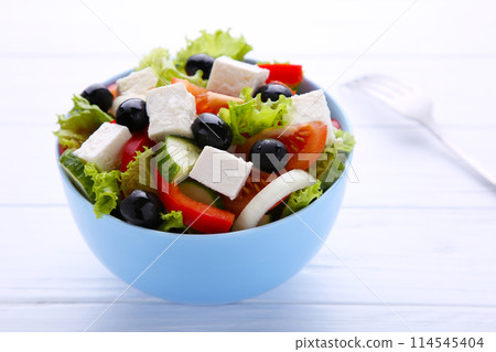 Fresh vegetable salad with fork on white wooden background Fresh vegetable salad with fork on white wooden background 114545404