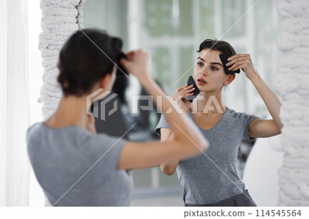 Facial skin care. A woman is doing a face massage using gouache stones. Facial skin care. A woman is doing a face massage using gouache stones. 114545564