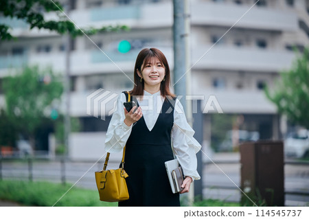 A young woman walking while operating a computer A young woman walking while operating a computer 114545737