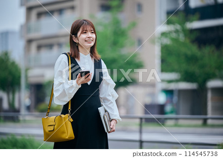 A young woman walking while operating a computer A young woman walking while operating a computer 114545738