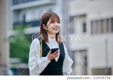 A young woman walking while operating a computer A young woman walking while operating a computer 114545739