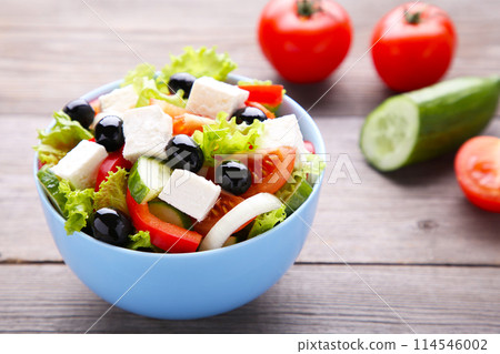 Fresh greek salad on bowl with vegetables on grey wooden background Fresh greek salad on bowl with vegetables on grey wooden background 114546002