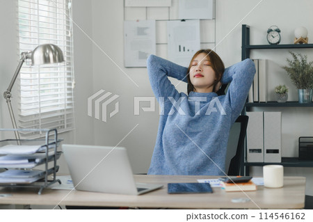 Young woman taking a relaxing stretch break in her home office during work. 114546162