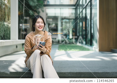 A cheerful young woman engaging with social media on her smartphone, receiving likes and reactions while holding a coffee cup outdoors. 114546265