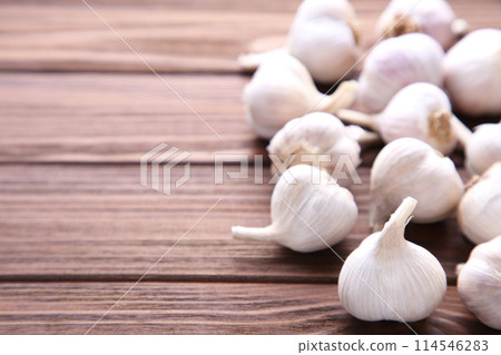 Fresh garlic on a brown wooden background Fresh garlic on a brown wooden background 114546283