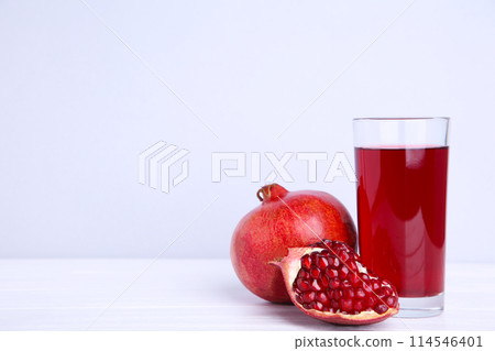Ripe pomegranate and fruit juice glass on grey background 114546401
