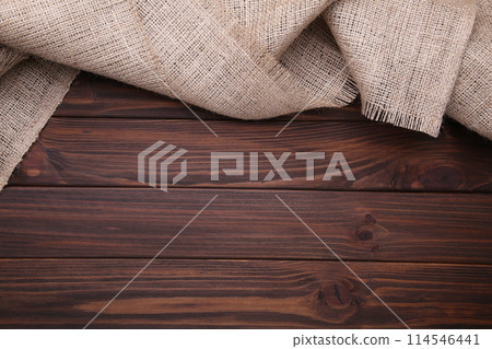 Natural sackcloth on brown wooden background. Canvas on brown wooden table Natural sackcloth on brown wooden background. Canvas on brown wooden table 114546441