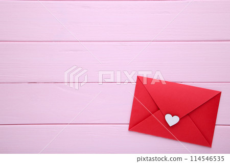 Red envelope with white heart on pink wooden table 114546535