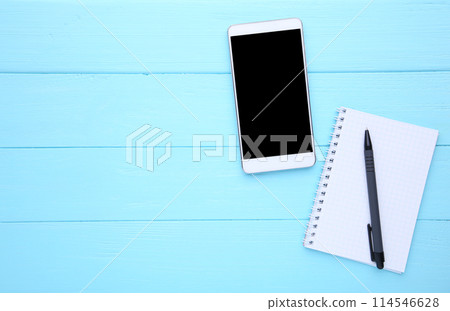 Smart phone with notebook on blue wooden background 114546628