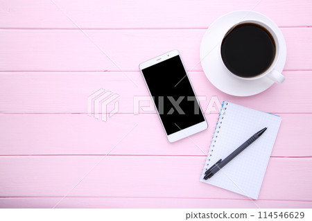 Smart phone with notebook and cup of coffee on pink wooden background 114546629