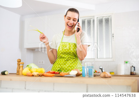 Young woman cooking dinner at home, talking on phone Young woman cooking dinner at home, talking on phone 114547638