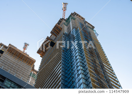 Upward view of modern skyscraper against blue sky 114547909