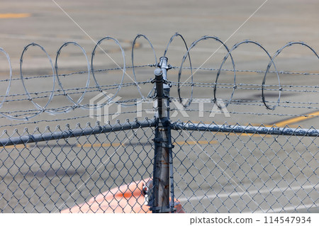 Security barbed wire on airport perimeter fence 114547934