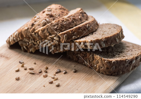 Sliced rye bread with sunflower seeds on wooden cutting board 114549290