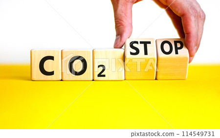 CO2 stop symbol. Concept word CO2 or CO2 stop on a beautiful wooden cubes. Beautiful yellow table white background. Businessman hand. Business ecological and CO2 stop concept. Copy space. 114549731