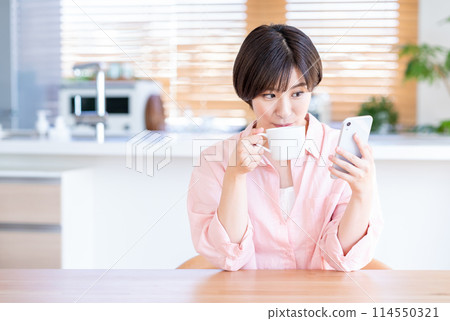 A woman who operates a smartphone in the living room. A woman who operates a smartphone in the living room. 114550321