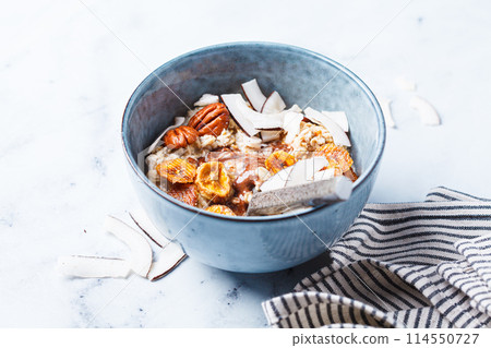 Overnight oatmeal with chocolate, pecans, coconut chips and dried banana, white background. Overnight oatmeal with chocolate, pecans, coconut chips and dried banana, white background. 114550727
