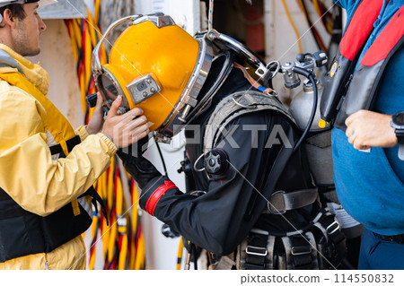 Tender assisting diver with gear after dive 114550832