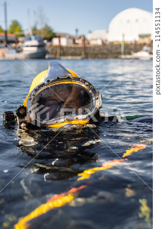 Commercial diver in helmet gazes at camera Commercial diver in helmet gazes at camera 114551134