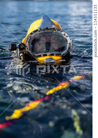 Commercial diver in helmet gazes at camera Commercial diver in helmet gazes at camera 114551135