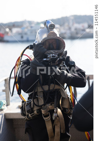 Commercial diver entering water in protective helmet 114551146