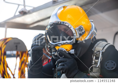 Commercial diver entering water in protective helmet 114551148