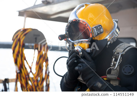 Commercial diver entering water in protective helmet 114551149