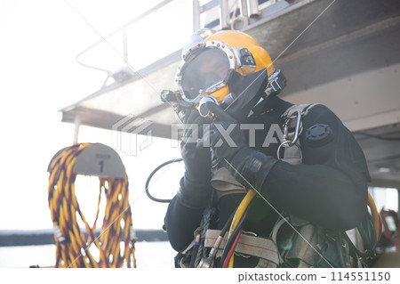 Commercial diver entering water in protective helmet Commercial diver entering water in protective helmet 114551150