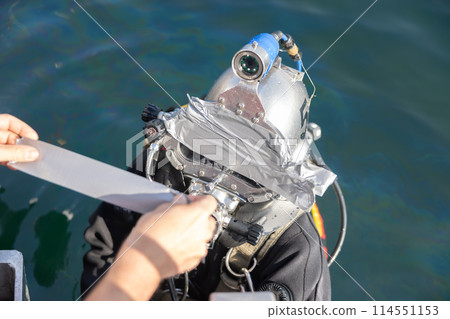 Commercial diver entering water in protective helmet Commercial diver entering water in protective helmet 114551153