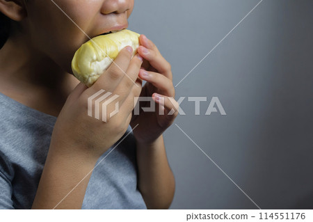 Close-up of a woman eating a ripe durian. 114551176