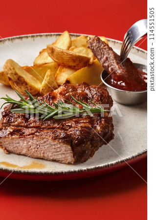 Sliced pork steak with baked potato wedges and barbecue sauce 114551505