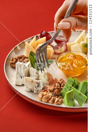 Woman savoring gourmet cheese platter against red background 114551515