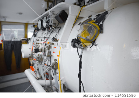 Side view of hyperbaric chamber with valves and pipes 114551586