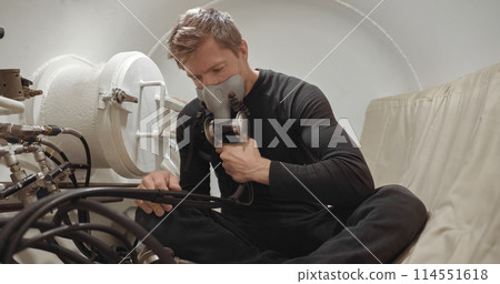 Military man receiving treatment in industrial hyperbaric chamber 114551618